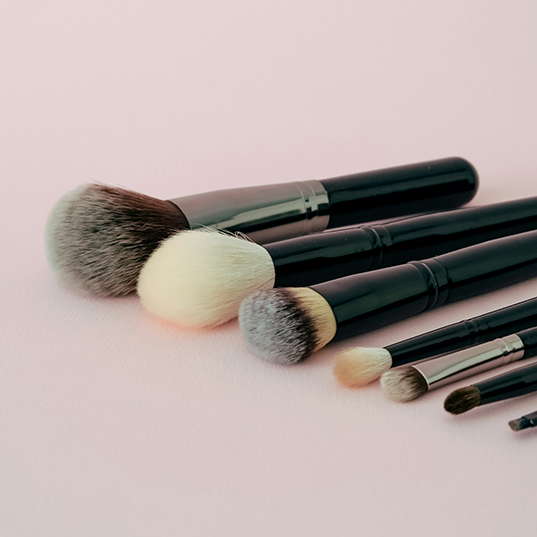 Set of makeup brushes on a light pink background